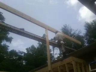 Carpenter setting a ridge beam over a new addition frame — Ice Dam Removal by Roofing Brothers in Bonneau