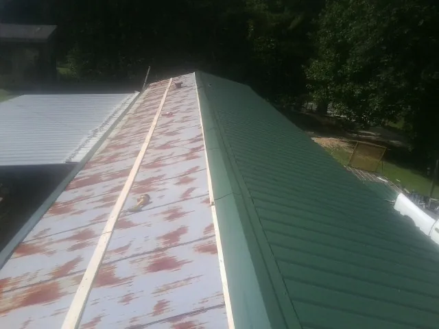 Old rusted panels beside newly installed green metal roofing — Wind Damage Roof Repair by Roofing Brothers in Bonneau