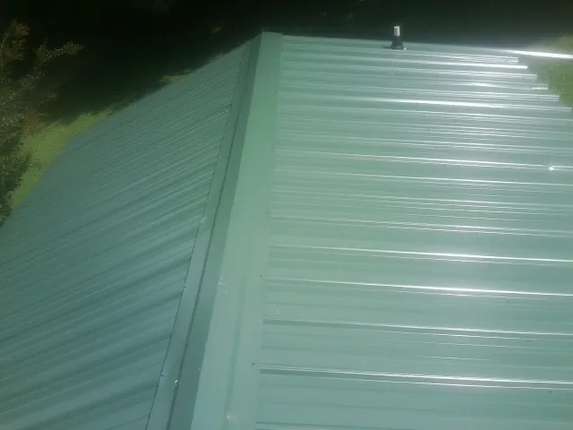 New green metal panels meeting at the ridge of a roof — Flat Roof Repair work by our crew in Bonneau