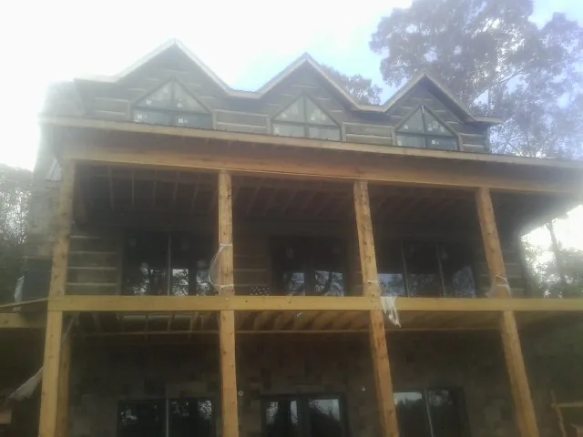 Dormers and porch framing on a large log home under construction — Roof Coating work by our crew in Bonneau
