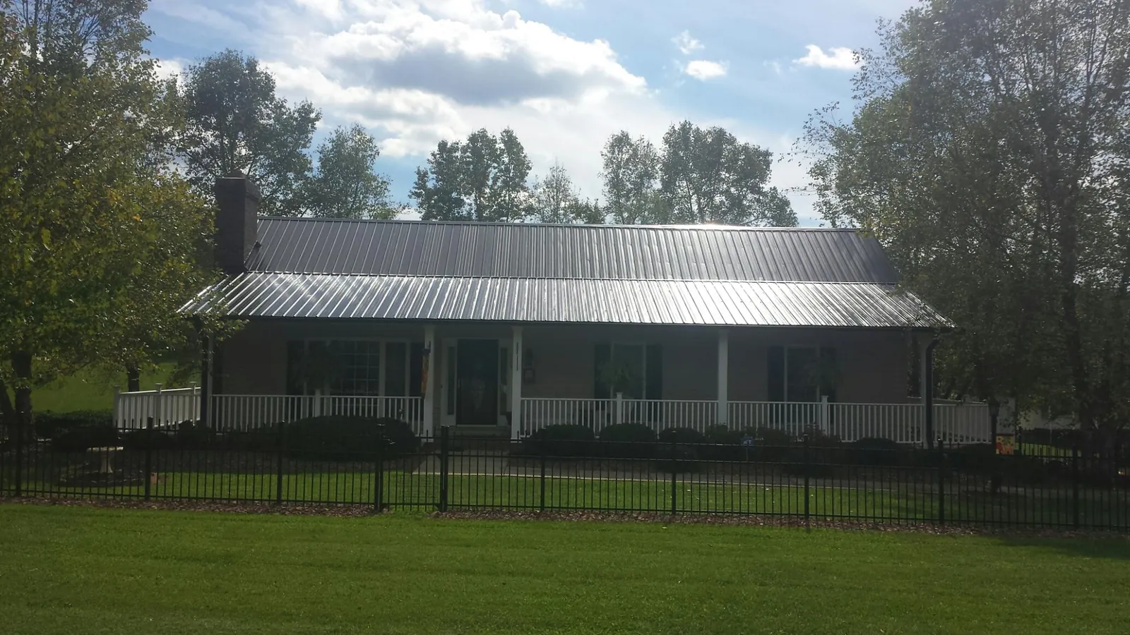 Gray metal roof on a brick ranch with a full width front porch — Gutter Guard Installation work by our crew in Bonneau
